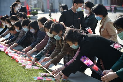 La gente deposita flores ante las estatuas de los difuntos líderes norcoreanos Kim Il-sung y Kim Jong-il como parte de las celebraciones del 110 aniversario del nacimiento de Kim Il-sung, conocido como el "Día del Sol". en Pyongyang el 15 de abril de 2022
