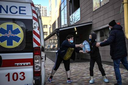 La gente descarga agua de una ambulancia en el hospital pediátrico de Kyin el 28 de febrero de 2022. 