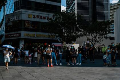 La gente espera a la sombra antes de cruzar la calle en Singapur. la temperatura anual promedia los 31 grados