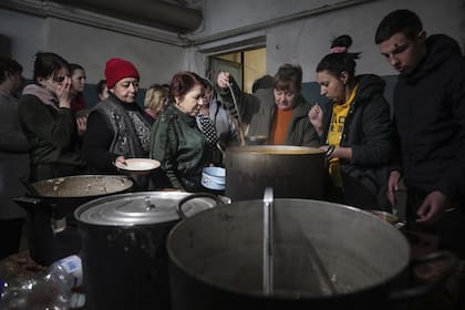 La gente hace cola para recibir comida caliente en un refugio antibombas improvisado en Mariupol, Ucrania, el 7 de marzo de 2022.