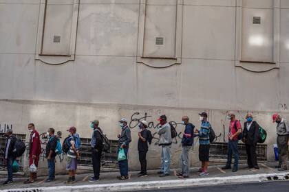 La gente hace fila para obtener comida frente a una organización benéfica católica en São Paulo. Decenas de millones de brasileños enfrentan hambre o inseguridad alimentaria a medida que se prolonga la crisis del COVID-19