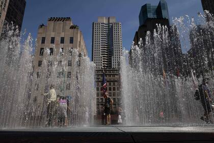 La gente juega en la escultura a base de agua del artista Jeppe Hein titulada "Changing Spaces" en el Rockefeller Center Plaza en Nueva York 