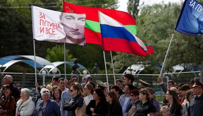 La gente lleva una bandera rusa y una bandera con un retrato del presidente ruso Vladimir Putin que dice "¡Estamos a favor de Putin!" en Tiraspol, la ciudad principal de la región separatista de Transnistria.