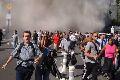 La gente lucha por ponerse a salvo frente al Ayuntamiento cuando la primera torre del World Trade Center se derrumba