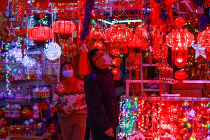 La gente mira las decoraciones festivas para el próximo Año Nuevo Lunar, que este año marca el Año del Buey, en un mercado en Shenyang, en la provincia de Liaoning, en el noreste de China, el 25 de enero de 2021