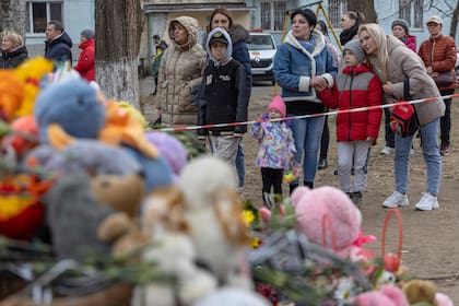 La gente observa los juguetes exhibidos afuera de un edificio de varios pisos gravemente dañado en Odessa el 3 de marzo de 2024, en el que murieron varios niños, en medio de la invasión rusa de Ucrania