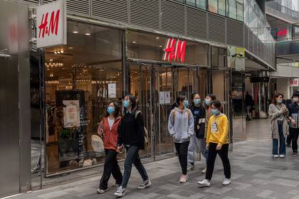 La gente pasa frente a una tienda de H&M en Pekín el 5 de abril de 2021