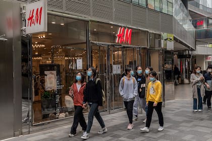 La gente pasa frente a una tienda de H&M en Pekín el 5 de abril de 2021