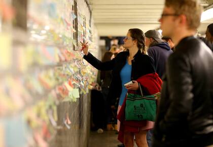 La gente pega sus mensajes escritos en post-its como parte del proyecto 'Subway Therapy', en el metro de Nueva York