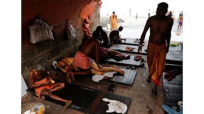 La gente recibe un masaje tradicional bajo un puente en las orillas del río Ganges en Kolkata