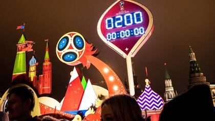 La gente se para frente al reloj digital de la Copa Mundial de la FIFA 2018 que se muestra exactamente 200 días antes del comienzo del torneo de fútbol de la Copa del mundo 2018, frente a la Plaza Roja y el Kremlin en Moscú