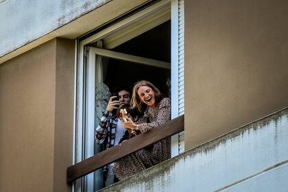 La gente se para junto a su ventana mientras el padre Nuno Westood viaja a bordo de un Smart convertible para rezar por los fieles que cumplen con el deber de quedarse en casa el domingo de Pascua debido al brote de coronavirus