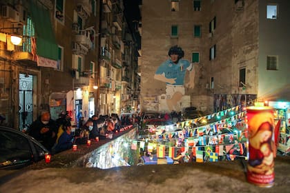 La gente se reúne en la cima del Quartieri Spagnoli en Nápoles junto a un mural de 1990 que representa a la leyenda del fútbol argentino Diego Maradona,
