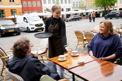 La gente se sienta en el exterior del restaurante Huks Fluks después de su reapertura en la plaza Graabroedre en Copenhague el 18 de mayo de 2020