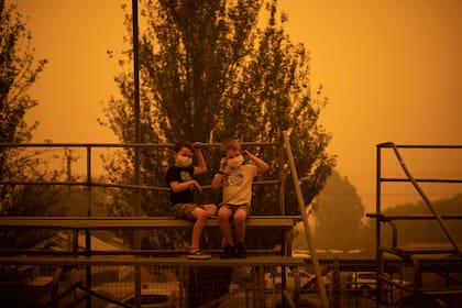 Niños juegan con mascaras protectoras en un parque de la ciudad de Bega, en el sur de Nueva Gales del Sur, donde acampan después de ser evacuados de sitios cercanos afectados por incendios forestales el 31 de diciembre de 2019.