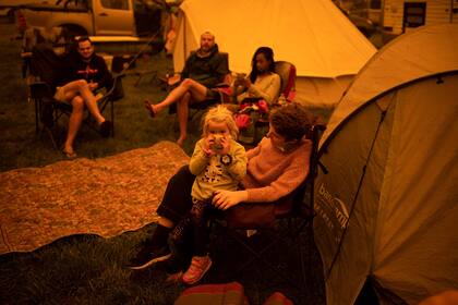 La gente se sienta y espera en un parque de la ciudad de Bega, en el sur de Nueva Gales del Sur, donde acampan después de ser evacuados de sitios cercanos afectados por incendios forestales el 31 de diciembre de 2019.