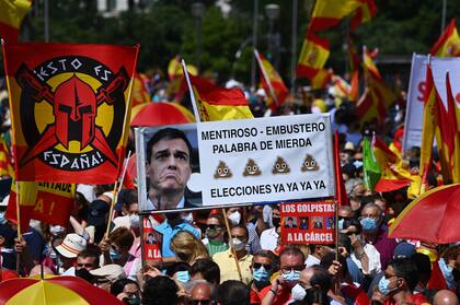 La gente sostiene una pancarta que muestra una foto del primer ministro de España, Pedro Sánchez, que dice "Mentiroso, elecciones ahora" durante una protesta de manifestantes de derecha para denunciar los controvertidos planes del gobierno español de ofrecer indultos a los separatistas catalanes encarcelados detrás de la fallida campaña de independencia de 2017, en Madrid, 13 de junio de 2021
