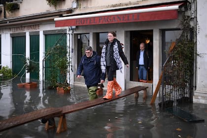 La gente usa una pasarela improvisada para salir de un hotel inundado