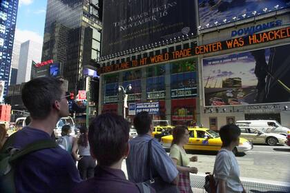 La gente ve pasar las noticias en Times Square sobre los ataques terroristas al World Trade Center en Nueva York, el martes 11 de septiembre de 2001
