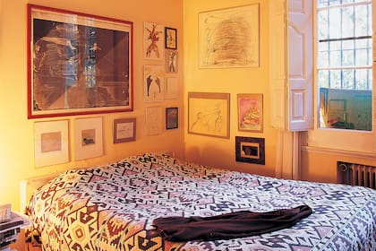 La gran cama de líneas sencillísimas y respaldo bajo, vestida con una manta traída de un viaje.