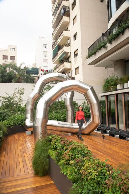 La gran escultura que simula a una lombriz se encuentra en un deck en donde es rodeada por una vegetación verde.
