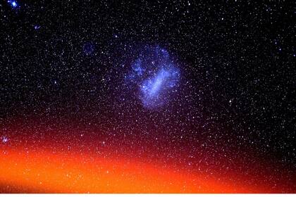 "La Gran Nube de Magallanes es visible en el hemisferio sur y la parte superior “rojiza-anaranjada” de nuestra atmósfera (llamada región f) se ve en la parte inferior de la fotografía". (X Don Pettit)