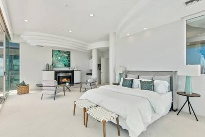 La habitación principal, con una decoración sofisticada en blanco y color agua, está alfombrada y tiene chimenea y terraza.