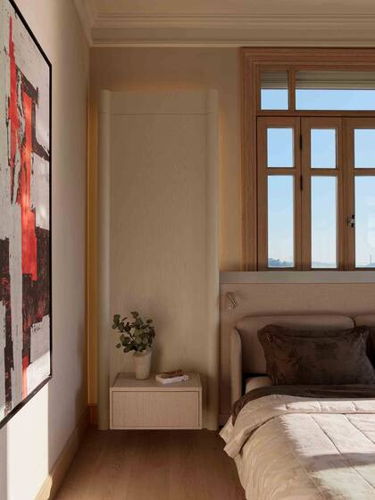 La habitación principal cuenta con pisos y aberturas en roble claro, complementados con una suave retroiluminación que enmarca la ventana.