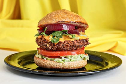 La hamburguesa falsa chicken de @plantabase.bsas viene con tofu, lechuga iceberg, emulsión de palta, tomate fresco, cilantro, queso cheddar, pickles de cebolla y papas fritas.