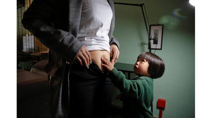 La hija de 3 años de Grace Yuan, Rebecca, toca la cicatriz de cesárea en el vientre de su madre, en Samurai Tattoo en Shanghai