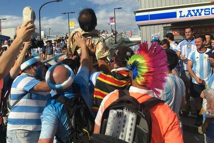 La hinchada argentina levanta a un aficionado japonés; mucha diversión fuera del estadio Tokyo.