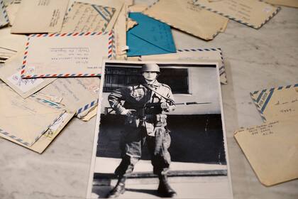 Marcelo exhibe una foto de soldado, con 18 años, en Malvinas; de fondo, las cartas que lo ayudaron a sobrevivir, a volver y a sostenerse cada día