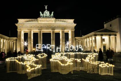  Activistas del Fondo Mundial para la Naturaleza (WWF) escriben las palabras "Hora del Planeta" con luces de led frente a la Puerta de Brandenburgo