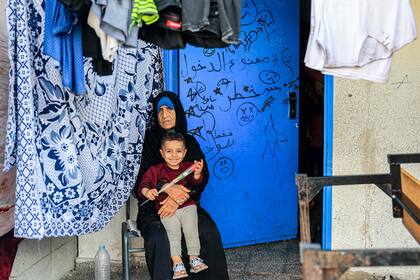 La imagen muestra a una mujer junto a un niño en una escuela dirigida por la Agencia de las Naciones Unidas para los Refugiados de Palestina en Oriente Próximo (UNRWA) en Rafah, en el sur de la Franja de Gaza, el 14 de noviembre de 2023. 
