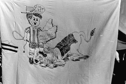 La referencia futbolística en una bandera con las mascotas de dos mundiales: el Gauchito del 78 y el León inglés del 66