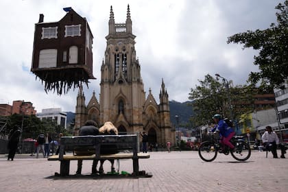 La instalación "Pulled by the Roots" muestra una casa con un sistema de raíces colgando. Está suspendida en el aire en el parque de Lourdes, como parte de la primera bienal de arte en Bogotá, Colombia