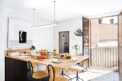 La isla de la cocina se hizo con una gran tabla de madera sobre un cubo en el que conviven el lavarropas, el lavavajillas, la bacha y los electrodomésticos pequeños. Por supuesto que la iluminación es de diseño propio: el modelo Tubus, de Contain.