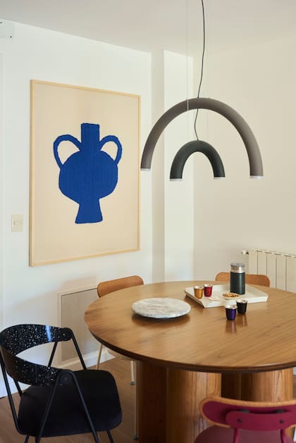 La lámpara 'C' de La Feliz, una menera de asociar la imagen curva y la luz lineal. Mesa de madera (Sol Larrosa) y sillas mixtas (La Feliz). Cuadro (Polonia).