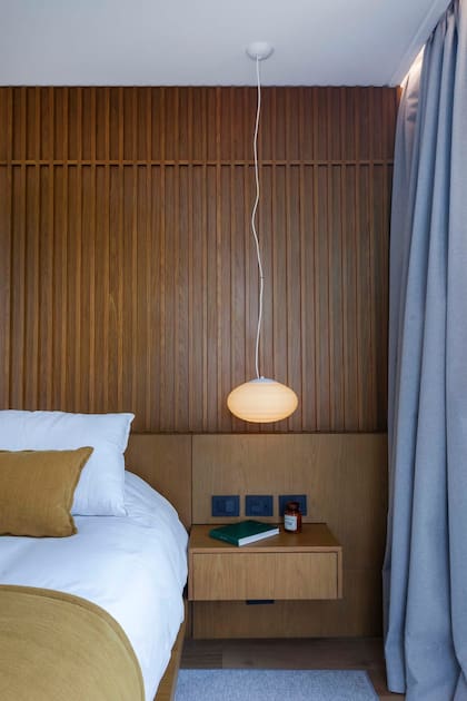 La lámpara ovalada impresa en 3D colgando de una línea fina y la mesa de luz flotante remiten a una estética japonesa depurada, donde cada objeto tiene un propósito y un lugar.