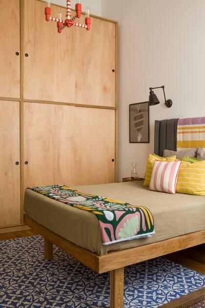 La lámpara rayada también fue idea y creación de los dueños de casa. La alfombra al pie de cama emula una trama de mosaicos, que mucho tiene que ver con la historia del departamento.