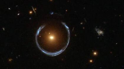 La lente gravitacional ha permitido al telescopio Hubble capturar la distante galaxia de la Herradura Azul, magnificada por la galaxia Roja Luminosa que se encuentra frente a ella