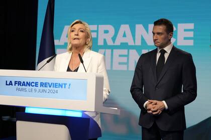 La líder de extrema derecha francesa Marine Le Pen habla mientras Jordan Bardella, presidente de la Agrupación Nacional de extrema derecha francesa, escucha en la sede del partido la noche de las elecciones después de que el presidente francés, Emanuel Macron, anunciara que disuelve la Asamblea Nacional y convoca nuevas elecciones legislativas tras la derrota en la votación de la UE, el domingo 9 de junio de 2024 en París.