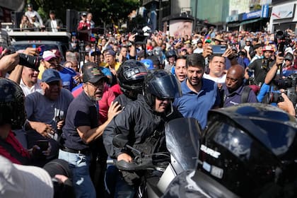 La líder opositora María Corina Machado con un casco y sentada en la parte trasera de una motocicleta mientras se la llevan después de dirigirse a la gente en una protesta contra el presidente Nicolás Maduro en Caracas, Venezuela, el jueves 9 de enero de 2025, el día antes de su toma de posesión para un tercer mandato. (AP Foto/Matías Delacroix)