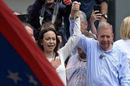 La líder opositora Maria Corina Machado levanta la mano de Edmundo Gonzalez Urrutia durante la campaña electoral de 2024. (Photo by Yuri CORTEZ / AFP)