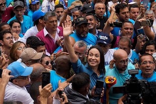 La líder opositora María Corina Machado saluda a sus simpatizantes mientras camina hacia una oficina para inscribirse para participar en las elecciones primarias de la oposición en Caracas, Venezuela, el viernes 23 de junio de 2023. (AP Foto/Ariana Cubillos)
