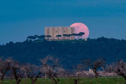 La luna llena sale detrás del Castel del Monte en Andria, Italia