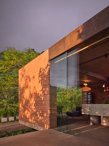 La luz del atardecer acentúa la textura de los muros de tierra y la conexión directa entre interior y paisaje.