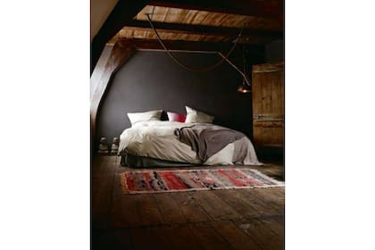 La madera en el techo, el piso y la puerta se ve acompañada por el tono marrón intenso del fondo, generando un cuadro cálido que invita al descanso