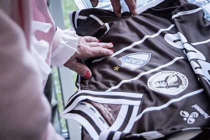 La mano de Haydee, de 98 años, acariciando la camiseta de Platense