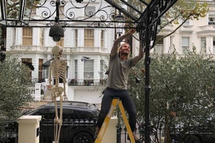 La mansión tiene una entrada de rejas de hierro negro con luces y un camino de azulejos en blanco y negro